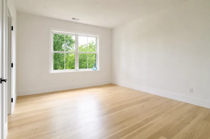Empty freshly cleaned room with light hardwood floors and a bright window